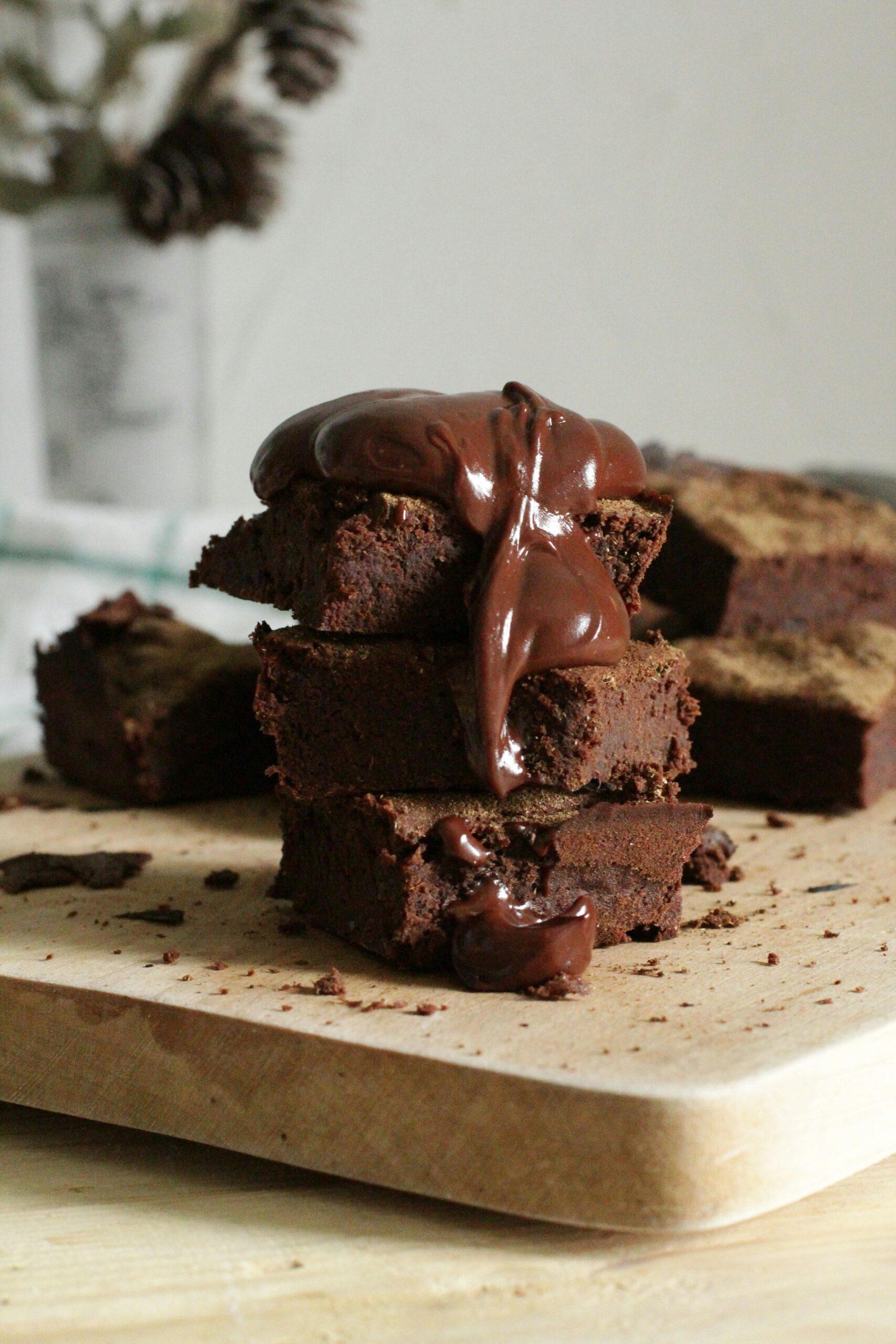 Delicious stack of chocolate brownies drizzled with gooey syrup on a wooden board.